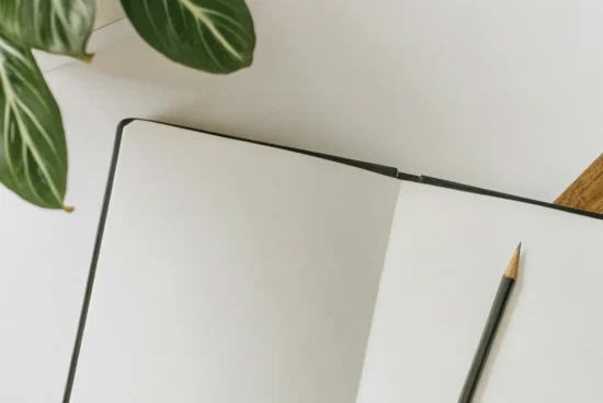 Open blank notebook with a pencil on a desk.